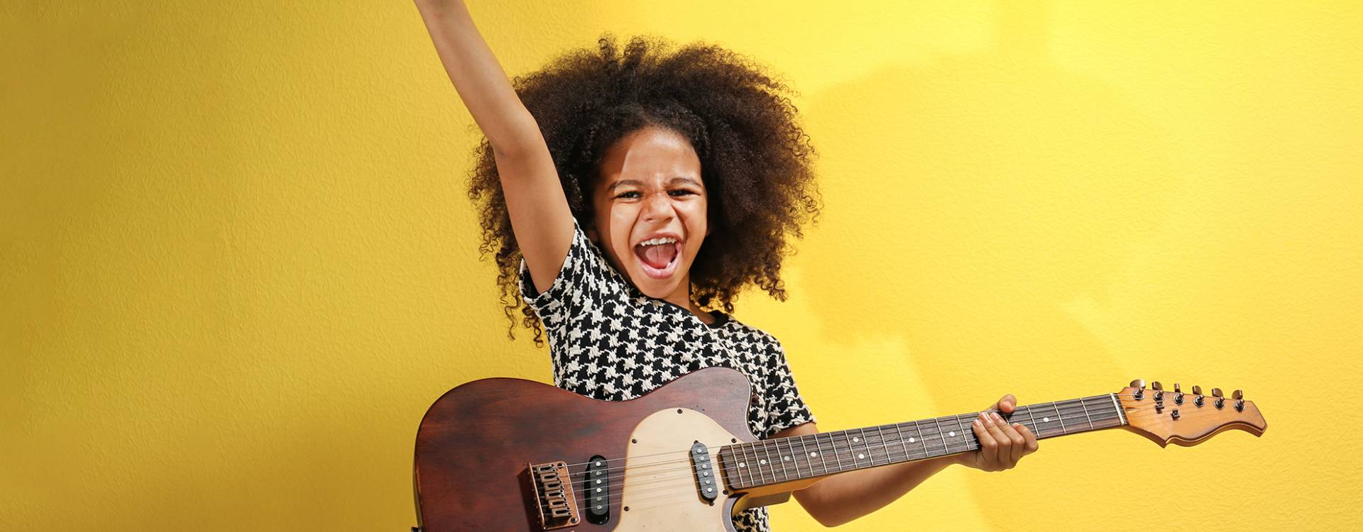 petite fille avec une guitare éléctrique sur fond jaune