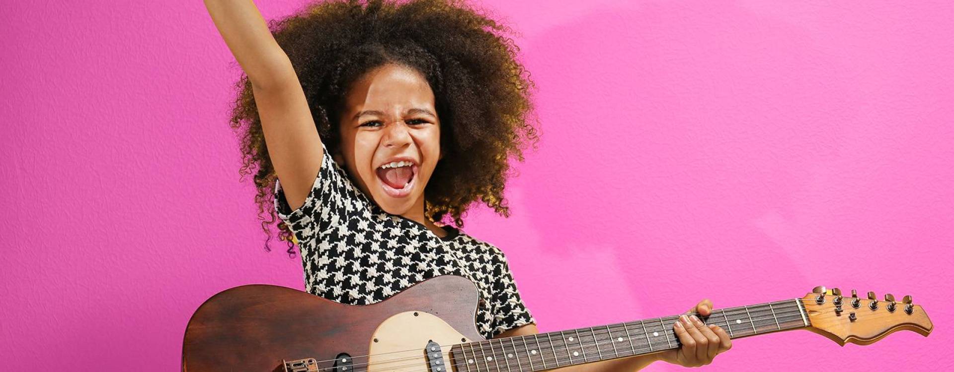 petite fille avec une guitare éléctrique sur fond mauve