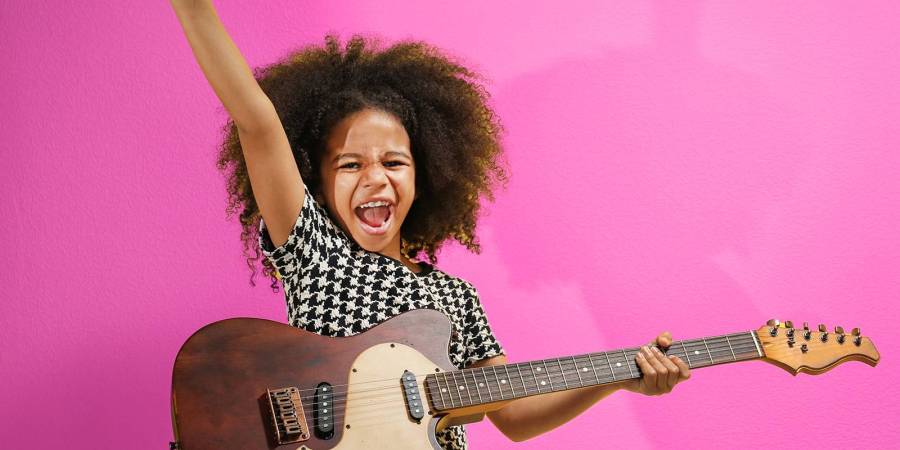 petite fille avec une guitare éléctrique sur fond mauve